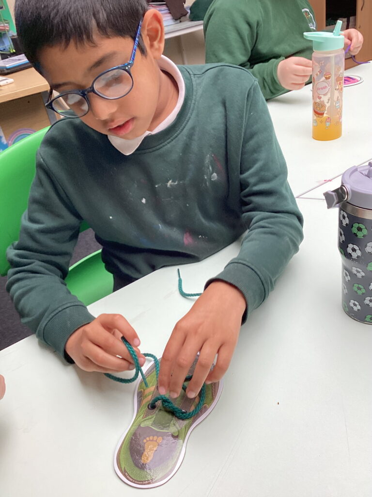 Maple Class learners proudly practise tying their own shoelaces, developing fine motor skills, coordination and independence through the Junior Duke Programme at The Rowan School.